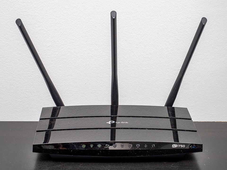 Black TP-Link AC1750 router with three antennas and front status lights.